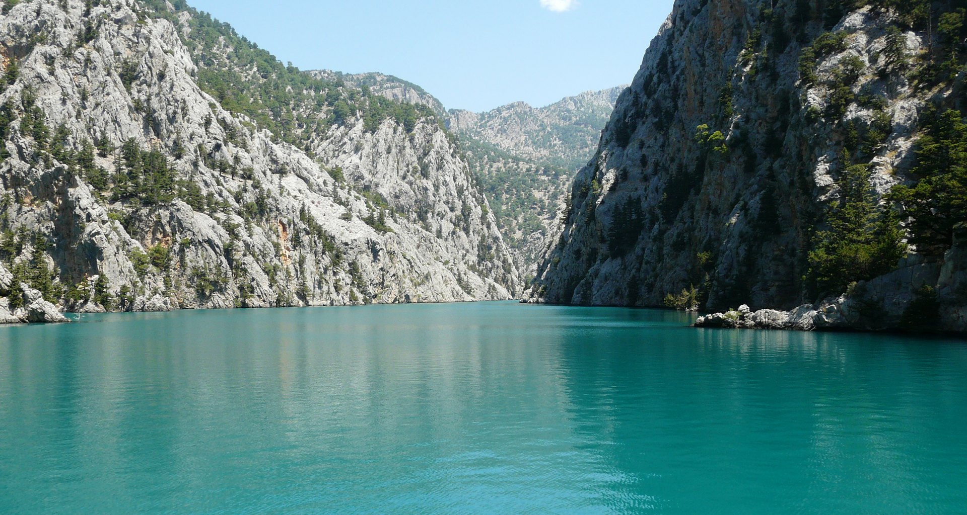 Green Canyon'da turkuaz suyun iki yanından yükselen dik kireç taşı kayalıklar