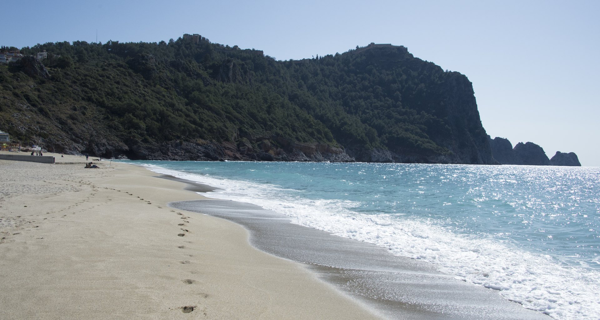 Alanya Kleopatra Plajı'nda sakin kumsal ve arka planda kale tepesi