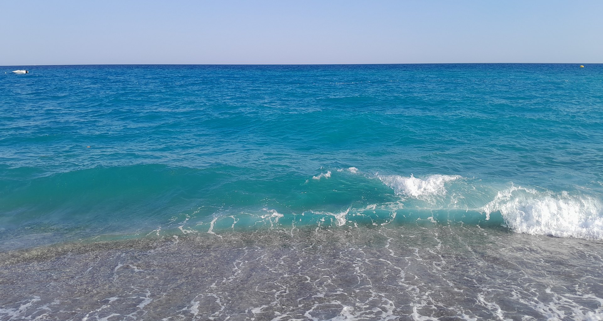 Antalya kıyısında Akdeniz'in turkuaz suları ve çakıl kumsalda kırılan dalga