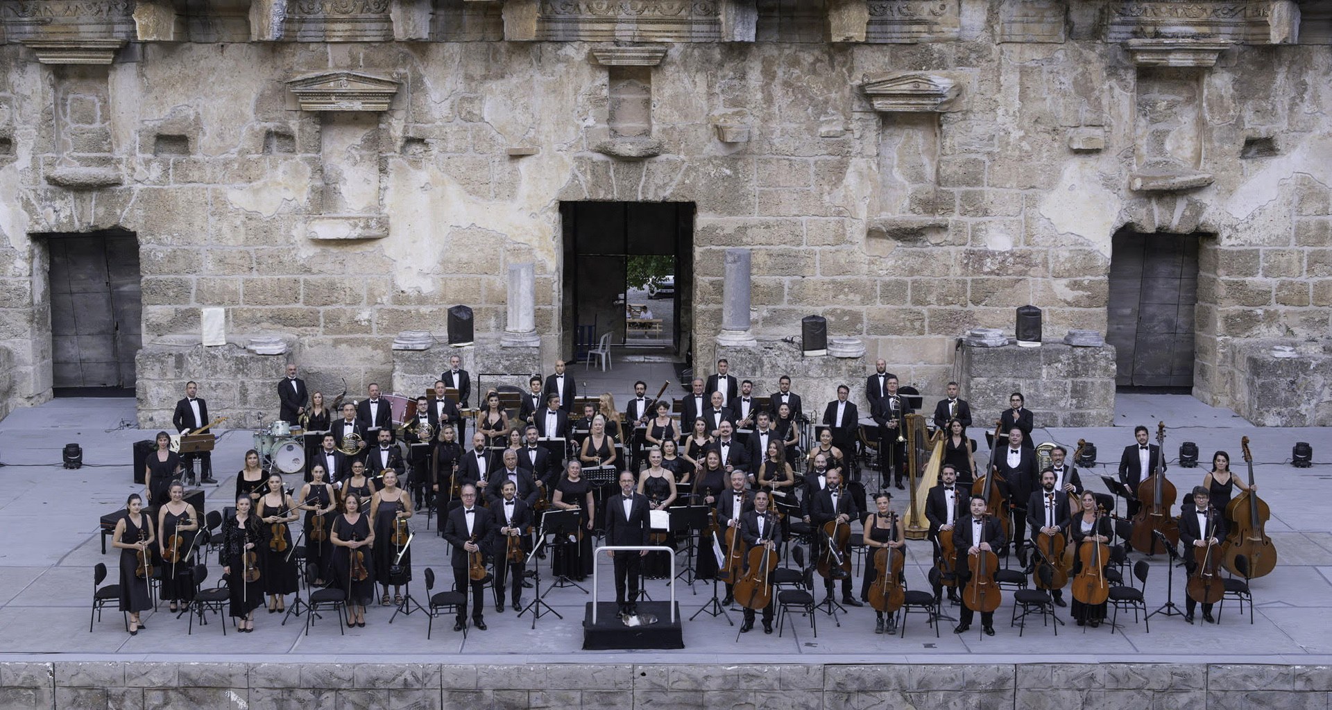 Aspendos Antik Tiyatrosu'nun sahnesinde konser veren bir senfoni orkestrası